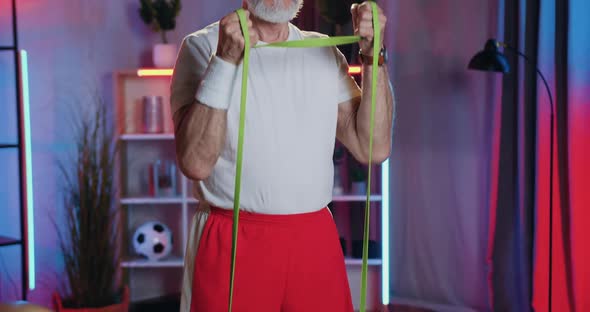 Old bearded Man in Sportswear Sports Exercising with Resistance Elastic Band