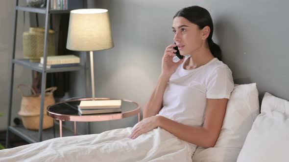 Angry Latin Woman Talking on Smartphone in Bed 