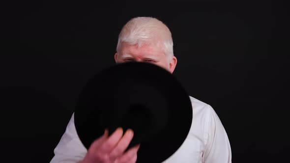 Bearded Man with Albinism Putting a Hat On, Isolated on Black Background.