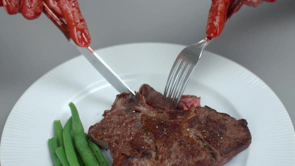 Bloody Male Hands Man Eats Beef Steak Cutting Off Piece of Meat on White Plate with Knife and Fork