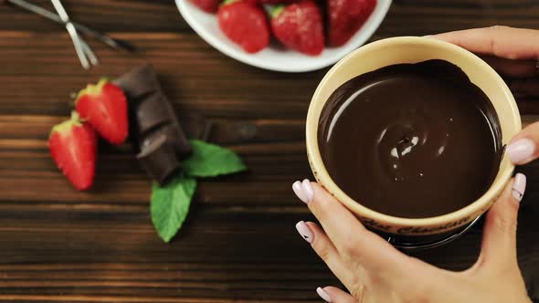 The Chef's Hands Put the Fondue on the Table. Fondue with Chocolate Strawberries on a Wooden