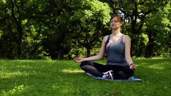 Girl is Meditating in Nature to the Music