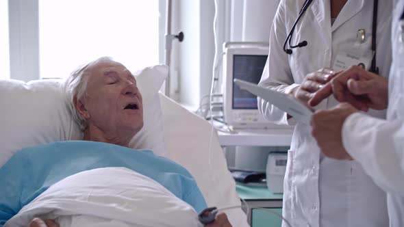 Medical Doctors Using Gadget while Speaking with Elderly Patient