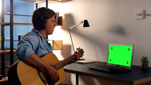 Man in Headphones Playing Guitar at Home