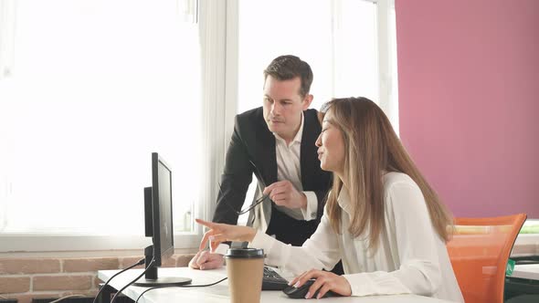 Young Businesss Ladies Sitting in Modern Office and Using Computer Discussing