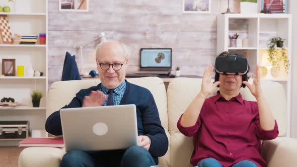 Elderly Age Woman Sitting on Sofa Wearing Virtual Reality Goggles