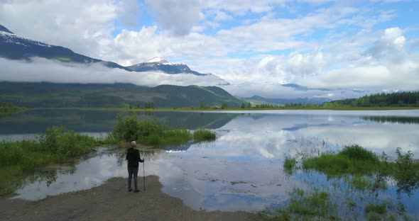 Aerial view of mature woman standing near a lake 4k