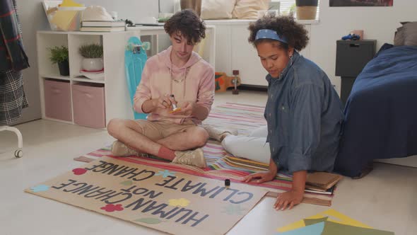 Girl and Guy Making Activist Slogan Sign