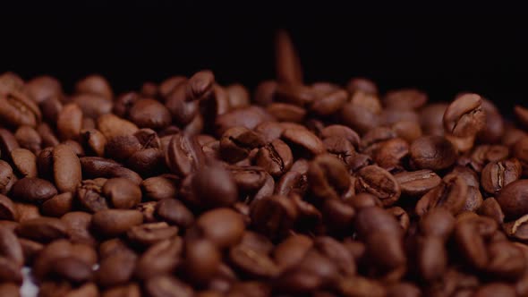 Falling brown roasted coffee beans in professional studio lights and black background.Macro footage.