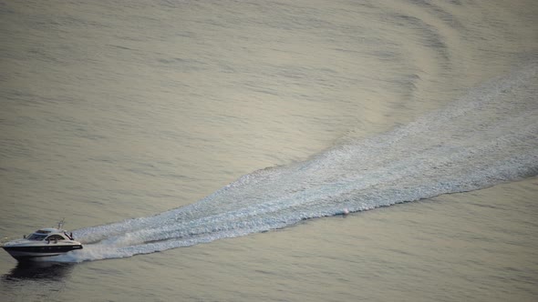 Speedboat Sailing Fast in a Calm Sea on Background of Sea Landscape with Rocky Coastline