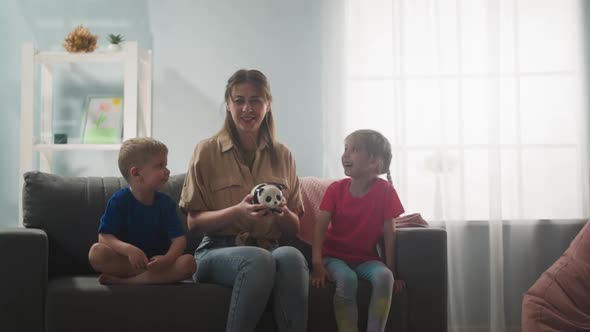 Young Mother with Children Shakes a Piggy Bank