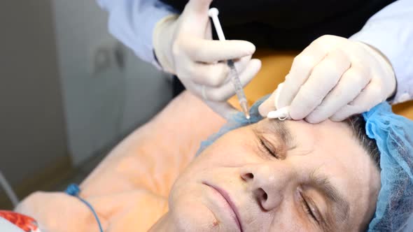 Close-up Shot of Beautician Applying Anesthesia Injection with Syringe To Senior Female Client