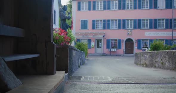 Moving out of large tunnel towards large statue and pink pastel hotel in Switzerland