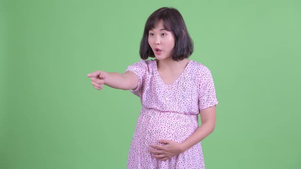 Happy Asian Pregnant Woman Pointing Finger