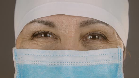 Close up of a caucasian female doctor smiling approvingly. Woman face in medical protective mask/