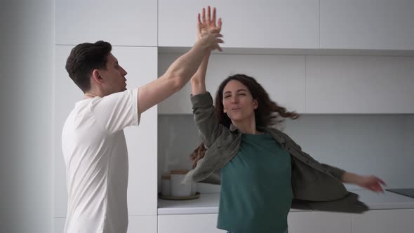 Married Couple Energetically Dancing in the Kitchen Hugging and Kissing
