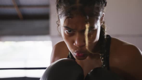 Mixed race woman using boxing gloves