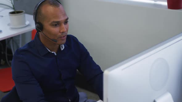 Mixed race businessman sitting using computers talking with phone headsets