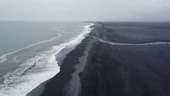 Flying over the southern coastline of Iceland as the Atlantic Ocean waves break on the black sand