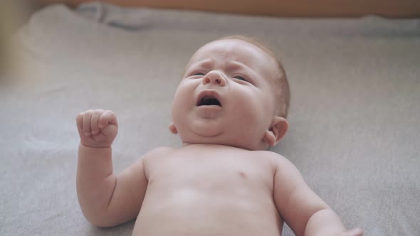 Newborn Son Lies on Baby Table and Nurse Performs Massage