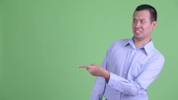 Stressed Asian Businessman Pointing Finger and Looking Disgusted