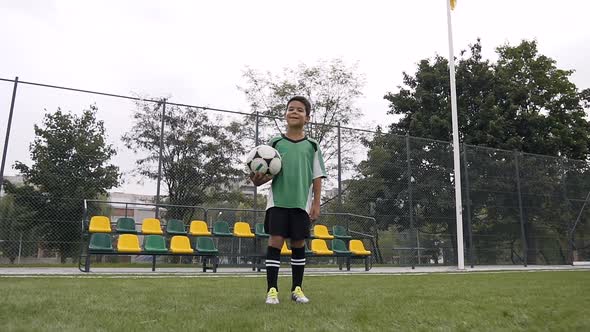 Happy Boy Looking to the Camera while Holding Soccer Ball