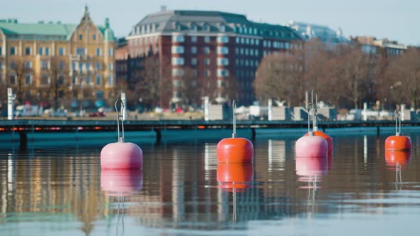 Red buoys floating on the water along the shoreline in Helsinki marina. Cityscape in background