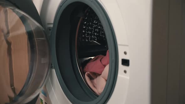 Women's Hands Put Clothes in a Modern Washing Machine