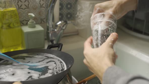 Washing a dirty glass with a sponge over a kitchen sink