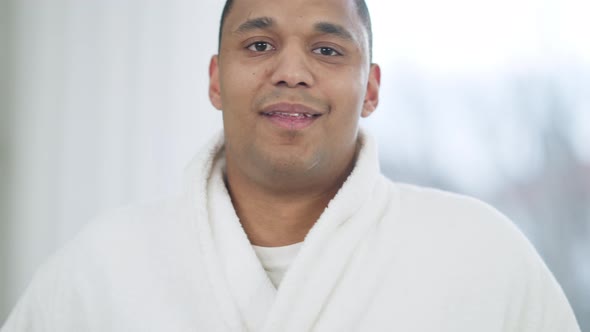 Closeup Portrait of Happy African American Young Man in White Bathrobe Looking at Camera Smiling