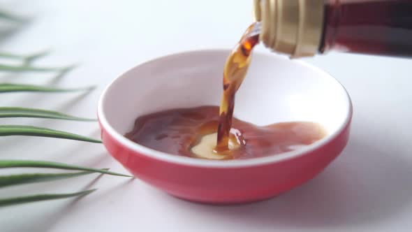 Pouring Soy Sauce in a Container with Leaf on White Background