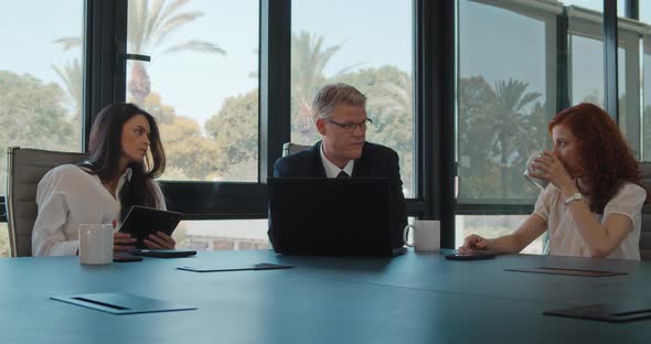 Group of three business people meeting in an office to work on a project. Slow motion