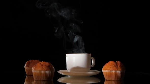 White Cup of Hot Smoking Coffee with Muffins on Dark Background