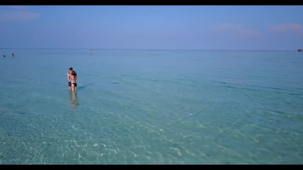 Romantic couple happy together on perfect tourist beach vacation by transparent lagoon and bright sa