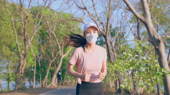 Asian young active sport woman wear mask run on street in public park.