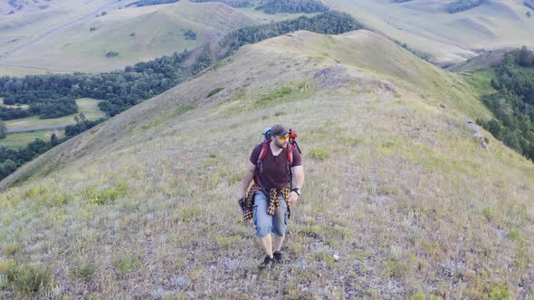 Aerial View of a Human Walking Along a Top of Hills.