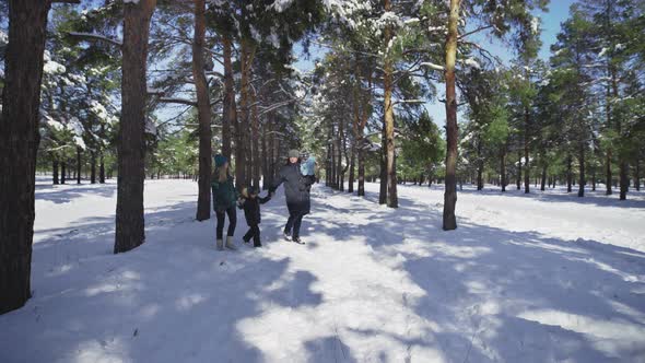 Young Family with Two Kids Walks in Winter Park with Snow