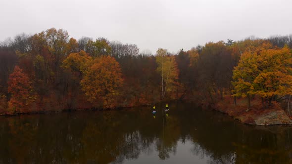 Drone Shot of Man and Woman on Sup Paddle Boards at Wide River on Golden Autumn Forest Background