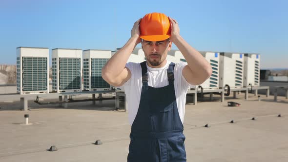 Portrait of a Young Engineer Who is Putting a Protective Helmet on His Head