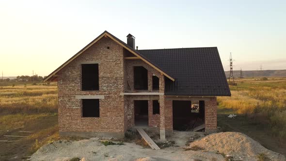 Aerial view of unfinished house with wooden roof structure covered with metal tile sheets under 