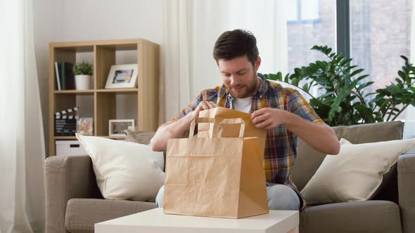 Smiling Man Unpacking Takeaway Food at Home