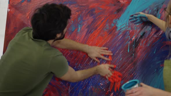 Man and Woman Painters Working Together in Art Studio on Large Canvas Using Hands