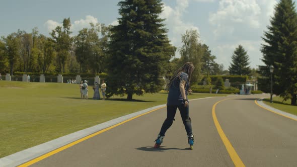 Woman Roller Riding Backwards Along Park Alley