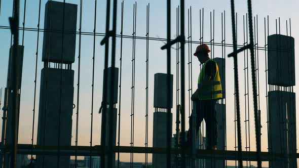 A Builder Works with Metal Constructions at a Building Site alt