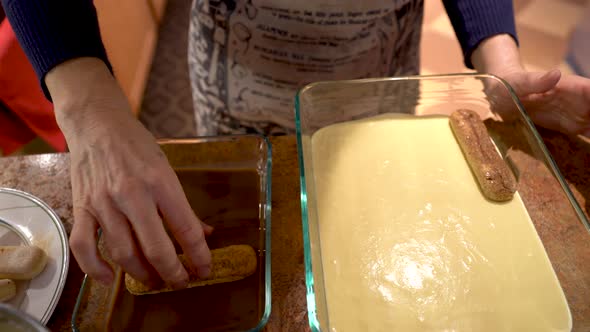 Closeup of chef putting second layer of lady fingers on top of the sabayon for tiramisu.
