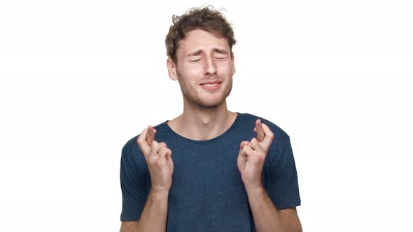 Portrait of Uptight Man 20s Wishing Good Luck Keeping Fingers Crossed Isolated Over White Background