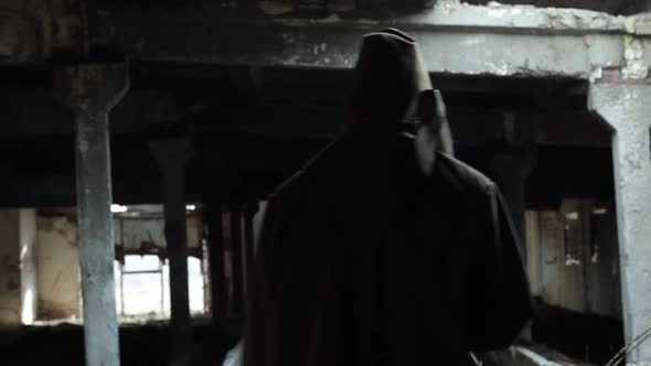 a Man in a Dark Cloak with a Bloody Ax Walks in a Dark Abandoned Room