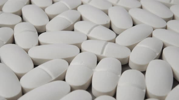 White oval pills close-up. The pile of medicines is spinning