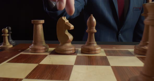 Male Hand Making Move with White Horse Knight on Chess Board Isolated Over Black Background