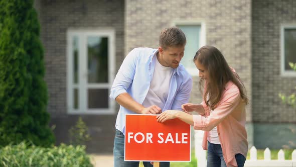Attractive Couple Hugging Installing for Sale Signboard in Front of House, Life